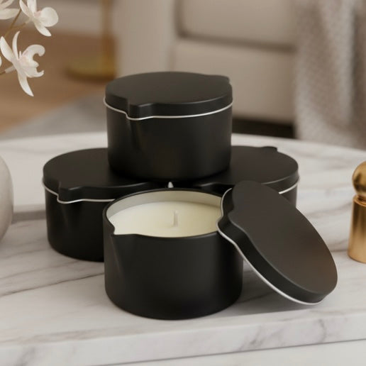 Black candle tins with a lit candle on a marble surface